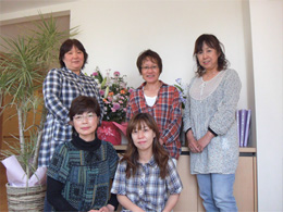 介護施設の入居者と職員による集合写真。室内でのレクリエーション場面。