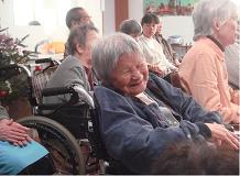 複数の高齢入居者が一堂に集まってレクリエーション・行事に参加している場面